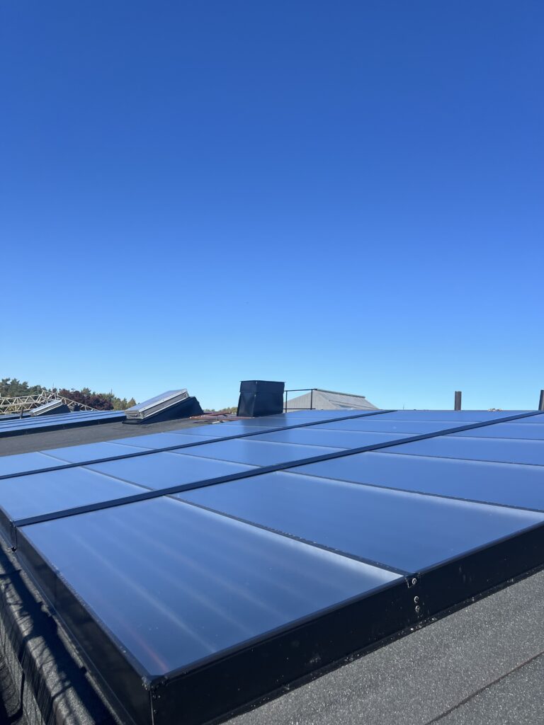 Solceller på ett tak, mot en blå himmel