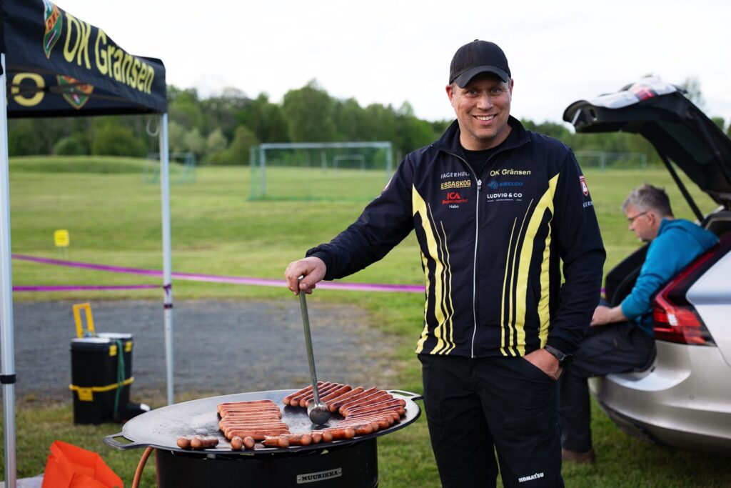 Man som grillar korv på orienteringstävling